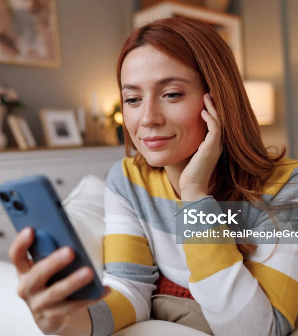 Frau schaut lächelnd auf ihr Smartphone